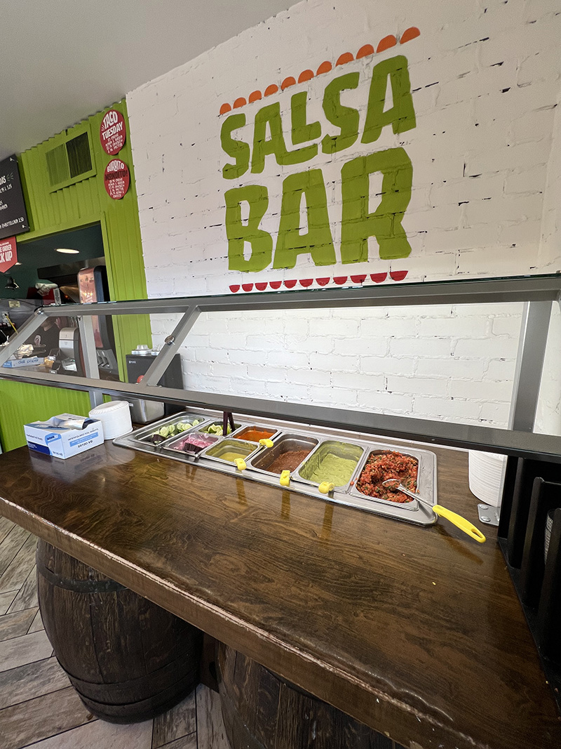Backyard Taco salsa bar with fresh salsa, lime, cucumbers, radishes, grilled onions, and jalapeños